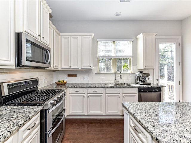 kitchen featuring appliances with stainless steel finishes, a sink, dark wood-style floors, and tasteful backsplash