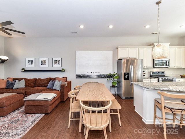 kitchen featuring light stone counters, dark wood-style flooring, decorative backsplash, appliances with stainless steel finishes, and white cabinetry