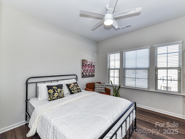 bedroom featuring a ceiling fan, wood finished floors, visible vents, and baseboards