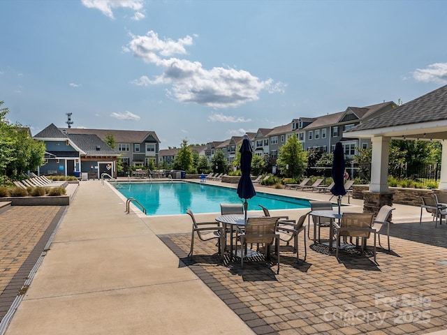 community pool featuring a residential view, a patio, and fence