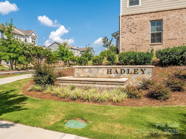 community / neighborhood sign featuring a residential view and a lawn