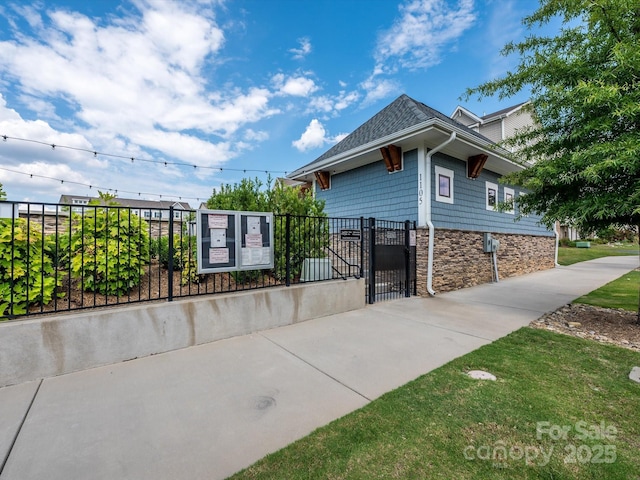 view of front facade with stone siding, fence, and a gate