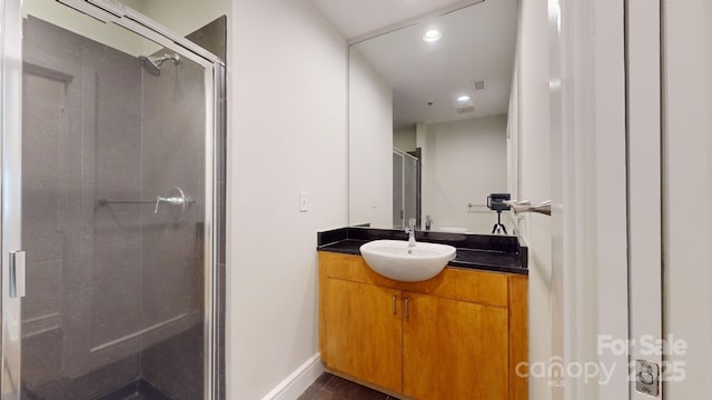 bathroom with recessed lighting, baseboards, a shower stall, and vanity