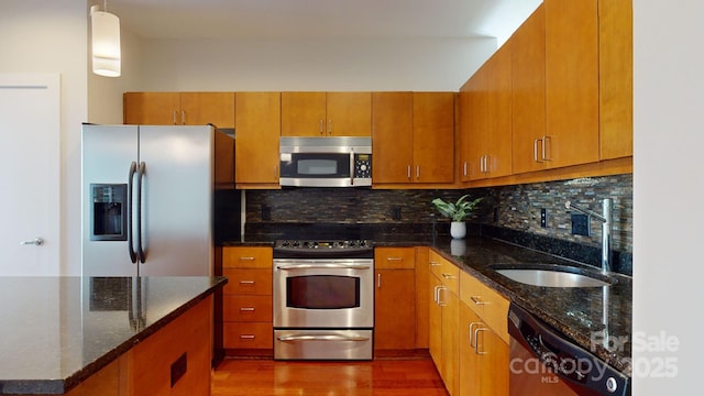 kitchen with appliances with stainless steel finishes, decorative backsplash, a sink, and brown cabinets