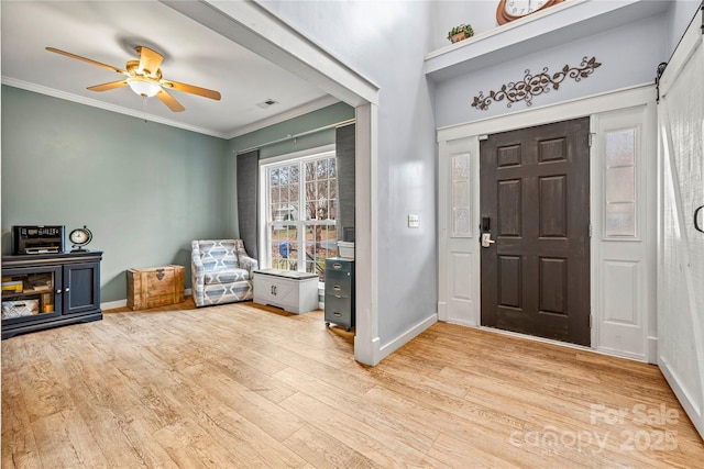 entrance foyer with baseboards, visible vents, ceiling fan, ornamental molding, and wood finished floors