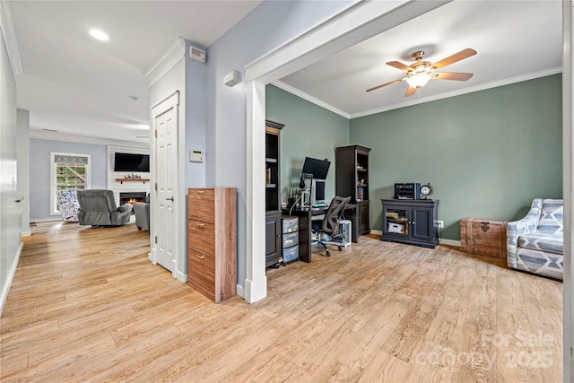 office space featuring ornamental molding, a warm lit fireplace, baseboards, and wood finished floors