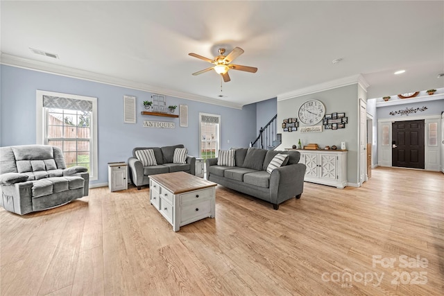 living area featuring visible vents, crown molding, light wood finished floors, and stairs