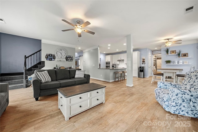 living room with stairs, ornamental molding, visible vents, and light wood-style floors