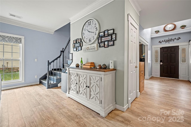 hallway with light wood-style floors, visible vents, stairway, and ornamental molding