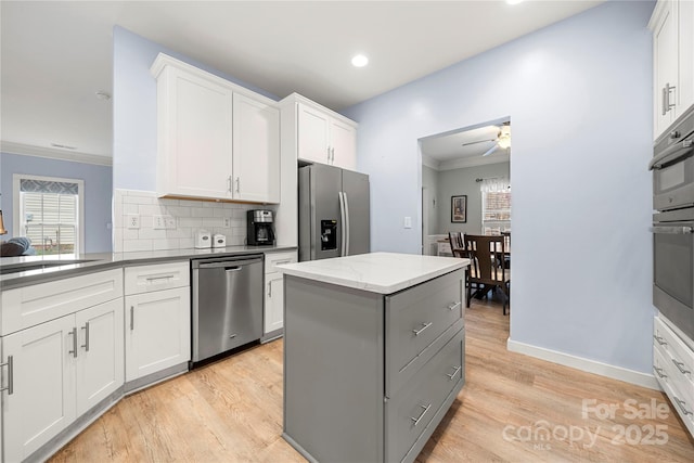 kitchen featuring light wood-type flooring, tasteful backsplash, stainless steel appliances, and crown molding