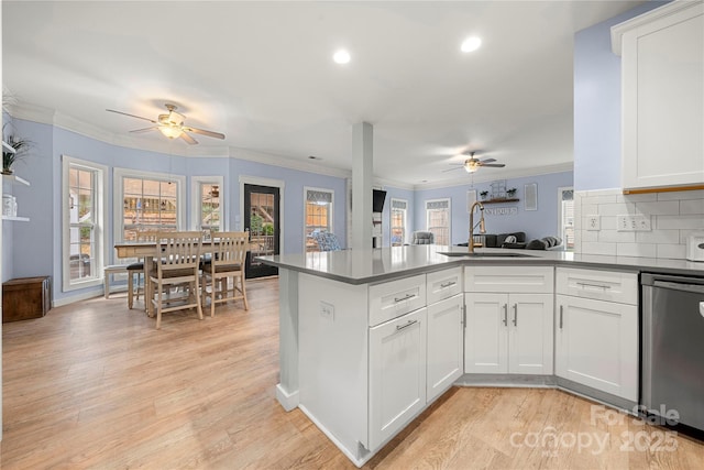 kitchen with crown molding, a wealth of natural light, a sink, dishwasher, and a peninsula