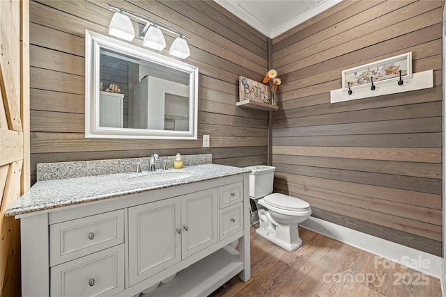 bathroom with wooden walls, vanity, toilet, and wood finished floors