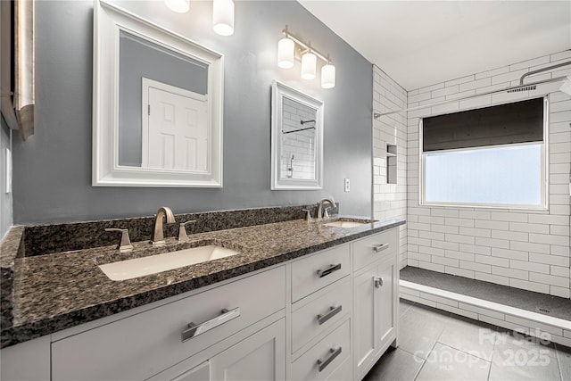 full bath with tile patterned floors, tiled shower, a sink, and double vanity