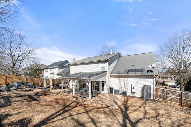 back of property featuring a fire pit, a patio area, a fenced backyard, and central AC unit