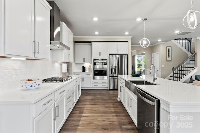 kitchen featuring hanging light fixtures, backsplash, appliances with stainless steel finishes, a sink, and wall chimney range hood