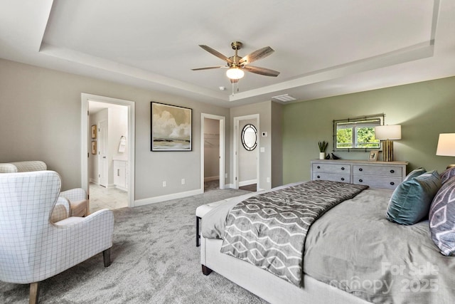 carpeted bedroom featuring a walk in closet, a raised ceiling, visible vents, ceiling fan, and baseboards