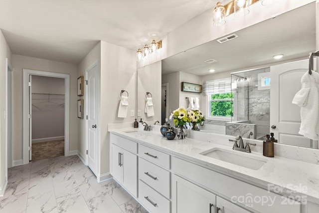 bathroom featuring visible vents, marble finish floor, a sink, and a shower with shower door