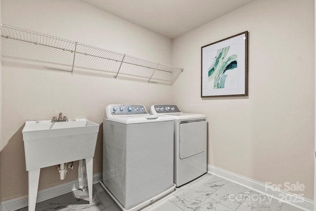 washroom with laundry area, baseboards, marble finish floor, washing machine and dryer, and a sink