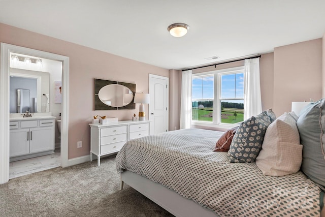 bedroom featuring carpet floors, visible vents, connected bathroom, a sink, and baseboards