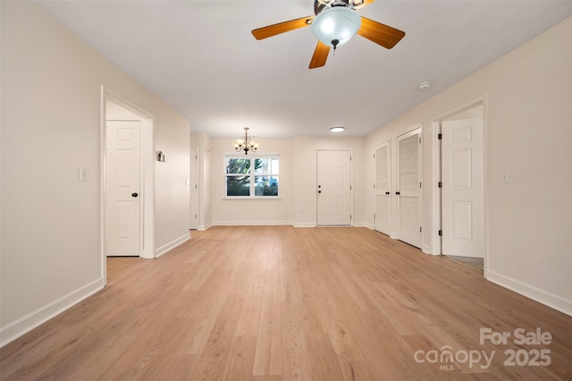 spare room featuring light wood-style flooring, ceiling fan with notable chandelier, and baseboards