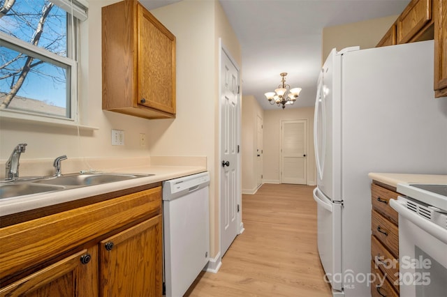 kitchen with white appliances, light wood-style floors, brown cabinets, and a sink