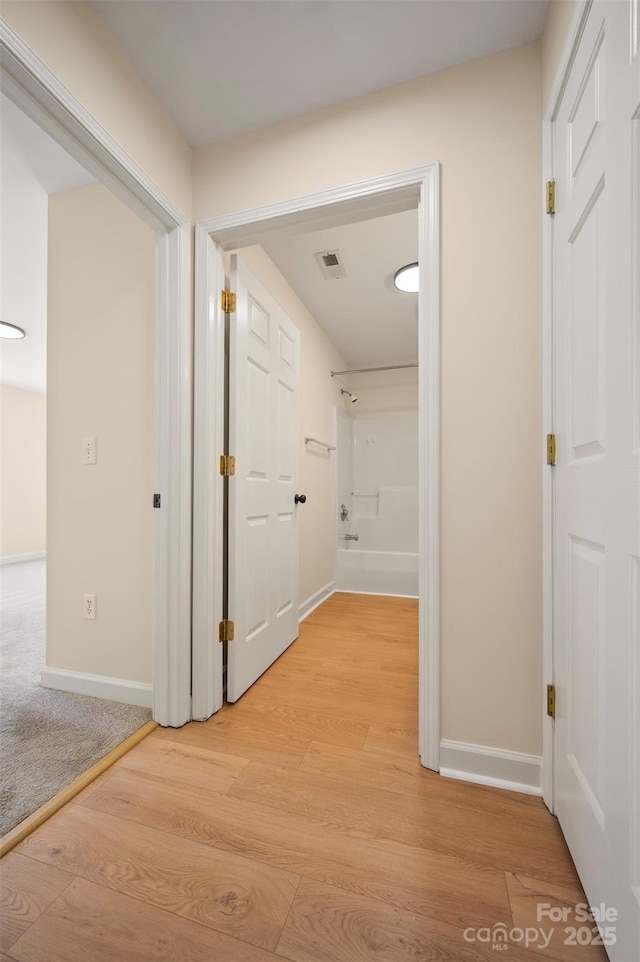 hallway featuring visible vents, baseboards, and light wood-style floors