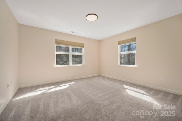 carpeted spare room featuring visible vents and baseboards