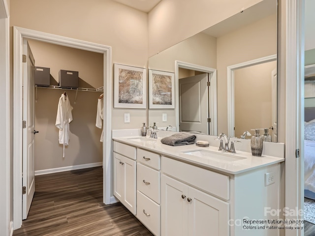 full bathroom featuring double vanity, a spacious closet, a sink, and wood finished floors