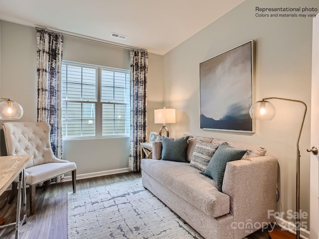 living room with wood finished floors, visible vents, and baseboards