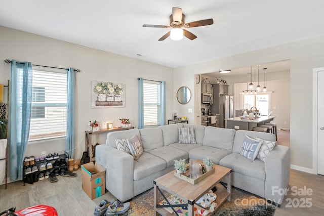 living area featuring a ceiling fan, baseboards, and wood finished floors