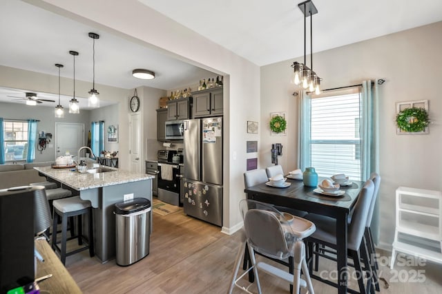 kitchen with light stone countertops, a wealth of natural light, stainless steel appliances, and a sink