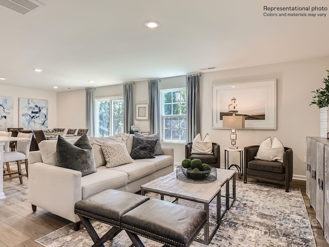 living room with light wood-style flooring, visible vents, baseboards, and recessed lighting