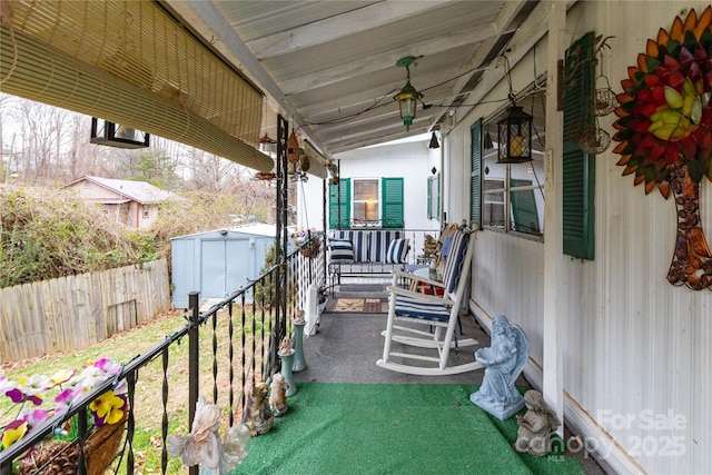 view of patio / terrace with a shed, covered porch, an outdoor structure, and fence