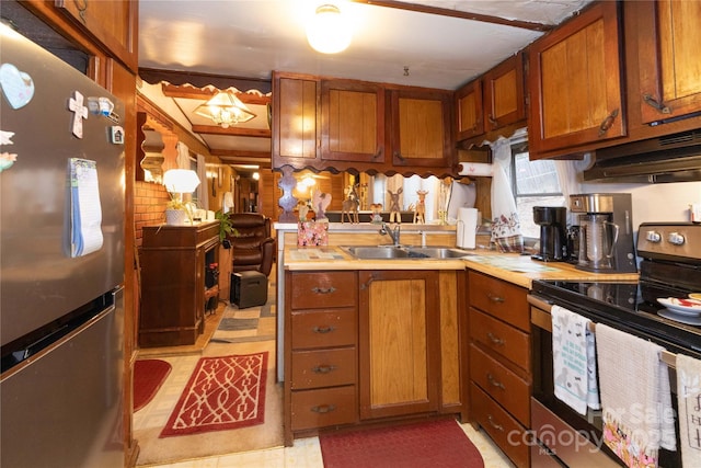 kitchen with light countertops, brown cabinetry, appliances with stainless steel finishes, and a sink