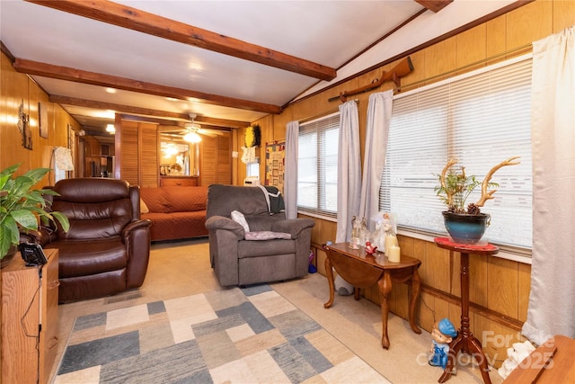 living room featuring beam ceiling, a ceiling fan, light colored carpet, and wood walls