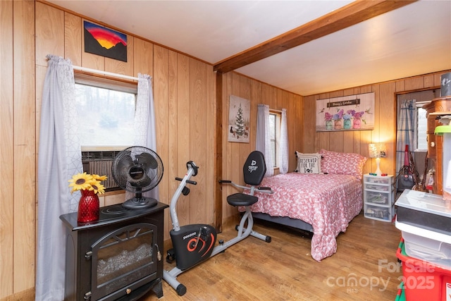 bedroom with beam ceiling, cooling unit, wood finished floors, and wood walls