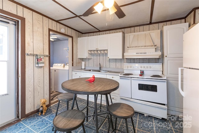 kitchen featuring a sink, under cabinet range hood, washing machine and dryer, white cabinetry, and white appliances