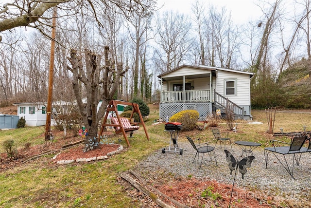 view of yard featuring a playground, a fire pit, and covered porch