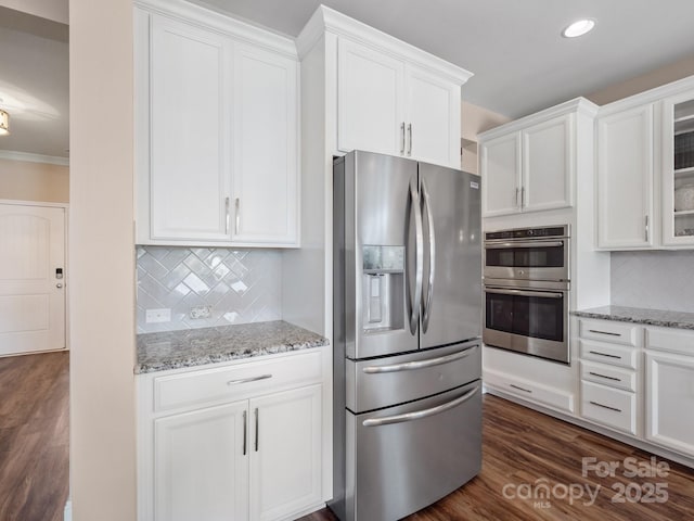 kitchen featuring dark wood-style floors, white cabinetry, appliances with stainless steel finishes, glass insert cabinets, and light stone countertops