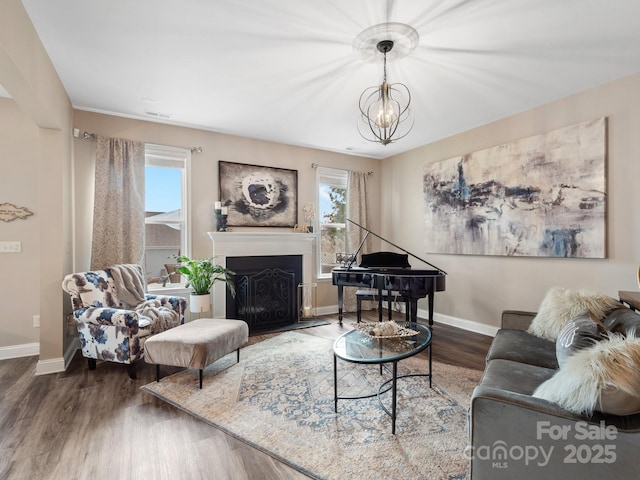 living room with a fireplace, an inviting chandelier, wood finished floors, and baseboards