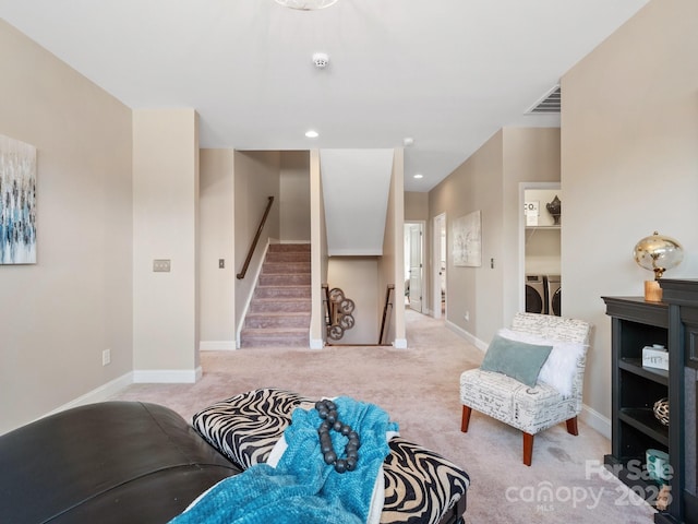 living area featuring light carpet, visible vents, washer and dryer, and baseboards