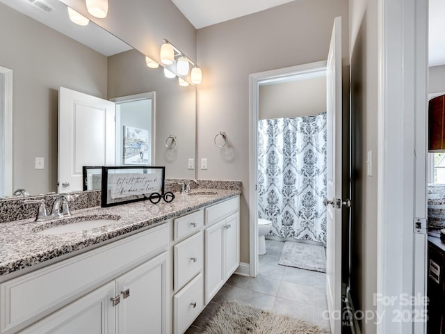 full bathroom with a sink, toilet, double vanity, and tile patterned flooring