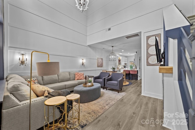 living area with a chandelier, visible vents, and light wood finished floors