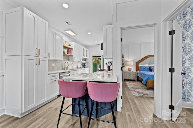 kitchen featuring light wood-style flooring, a sink, white cabinets, dishwasher, and open shelves