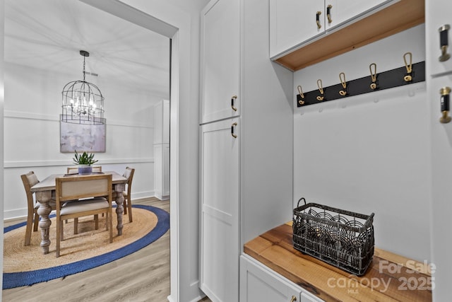 mudroom featuring light wood-style floors and a notable chandelier