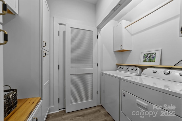 laundry area with washer and clothes dryer, wood finished floors, and cabinet space