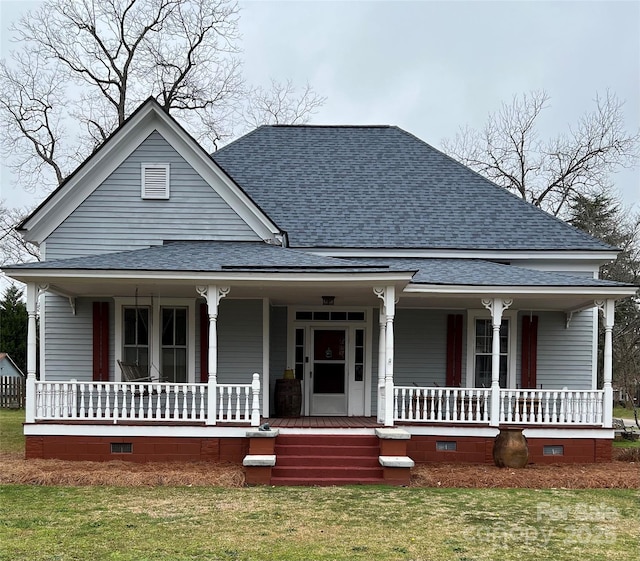 view of front of property with a front yard, crawl space, covered porch, and roof with shingles