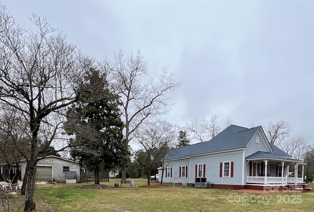 view of property exterior featuring covered porch, central AC, a detached garage, a yard, and roof with shingles