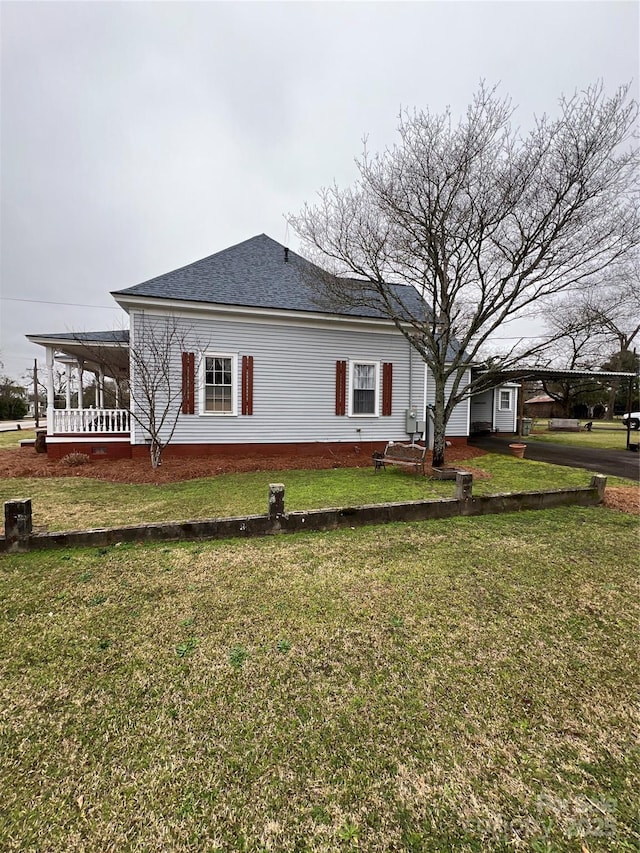 view of side of property with roof with shingles and a yard