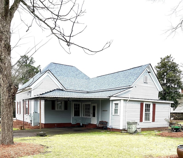 rear view of property featuring entry steps, a yard, and roof with shingles